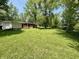 Spacious backyard with lush green grass, mature trees, and a cozy home with a porch at 725 N State Road 75, Lebanon, IN 46052