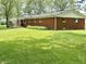 The backyard features a well manicured lawn, brick home, wooden deck, and lush greenery at 725 N State Road 75, Lebanon, IN 46052