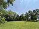Expansive lawn surrounded by mature trees under a bright blue sky adds natural beauty at 725 N State Road 75, Lebanon, IN 46052