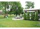 Landscaped backyard featuring a firepit with chairs, grill, evergreens, and a playset at 10113 Gallop Ln, Fortville, IN 46040