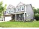 Beautiful two-story home featuring a brick facade, well-manicured lawn, and charming front porch with seating at 10113 Gallop Ln, Fortville, IN 46040