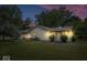 A dusk view of spacious backyard with a grass lawn and a patio area with a view of the home and some trees at 110 Leichester Ct, Noblesville, IN 46060