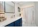 Bathroom with navy cabinets, a large mirror, and a shower with patterned curtains at 121 Wesley Cir, Noblesville, IN 46062
