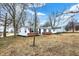 Lovely one-story house with a green roof, set against a backdrop of bare trees and a blue sky at 12471 N 100 E, Alexandria, IN 46001