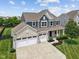 Elevated view of a brick and siding home with a three car garage and manicured lawn at 1306 Avocet Dr, Greenwood, IN 46143