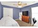 Blue accent bedroom with a bed, dresser, TV, and a bright window, providing ample natural light at 13191 Roma, Carmel, IN 46074