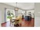 Dining room features wood floors and a view of kitchen with a dark blue island and white cabinetry at 13191 Roma, Carmel, IN 46074