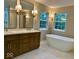Bathroom featuring double sinks, mirrors with lighting, a soaking tub, and windows at 13262 Landwood Dr, Fishers, IN 46037