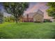 Backyard view showing lush grass, mature shade tree, brick home, and deck at dusk at 1411 N Claridge Way, Carmel, IN 46032