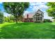 Expansive backyard view showcasing a lush lawn, mature trees, and a charming brick home with a deck at 1411 N Claridge Way, Carmel, IN 46032
