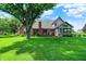 Large backyard view with mature trees, lush grass, and brick home with a deck at 1411 N Claridge Way, Carmel, IN 46032