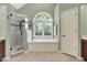 This luxury bathroom features a garden tub beneath an arched window and a glass enclosed shower at 1411 N Claridge Way, Carmel, IN 46032