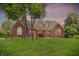 Charming brick home with a well-manicured lawn and mature trees during the twilight at 1411 N Claridge Way, Carmel, IN 46032