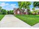 Brick home with a long driveway and a lush front yard with mature trees at 1411 N Claridge Way, Carmel, IN 46032