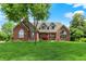 Charming brick home with a well-manicured lawn and mature trees under a sunny blue sky at 1411 N Claridge Way, Carmel, IN 46032