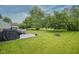 Expansive backyard with mature trees, a fire pit, a concrete patio, and access to a scenic pond at 16095 Tenor Way, Noblesville, IN 46060