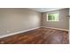 This empty bedroom has wood-look flooring, neutral walls, and a sunny window with a view at 16548 Grand Cypress Dr, Noblesville, IN 46060