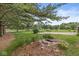 Spacious backyard with a rock lined pond, bordered by mature trees and open green space at 4010 S Bazil Ave, Indianapolis, IN 46239