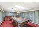 This basement features a pool table with a cover, a bar, and vintage wood paneling at 4010 S Bazil Ave, Indianapolis, IN 46239
