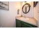 Stylish bathroom with a round mirror, unique wallpaper, and a sink with green cabinets at 4238 Victory Ct, Indianapolis, IN 46203