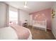 Bedroom with pink decor featuring a white crib, floral wall decorations and decorative gold mirror at 4238 Victory Ct, Indianapolis, IN 46203
