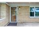 Inviting front entry featuring a storm door, brick facade, exterior lighting, and adjacent window at 5205 Staughton Dr, Indianapolis, IN 46226