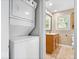 Bright bathroom with wood vanity, cabinet and stackable white washer and dryer at 57 E South St, Mooresville, IN 46158