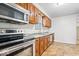 Compact kitchen featuring wood cabinets, tile floors, stainless steel appliances, and neutral walls at 57 E South St, Mooresville, IN 46158