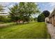 Expansive backyard with green grass, mature trees, and a wooden fence in the distance at 5749 Teresa Dr, Alexandria, IN 46001