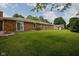 Brick home exterior displaying an expansive green lawn and mature trees, creating a serene backyard setting at 5749 Teresa Dr, Alexandria, IN 46001