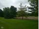 Spacious backyard with green grass, mature trees, and a wooden fence showcasing the property's boundary at 5749 Teresa Dr, Alexandria, IN 46001