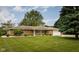 Charming brick ranch home featuring a lush green lawn, mature trees, and a two-car attached garage at 5749 Teresa Dr, Alexandria, IN 46001