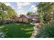 Beautiful backyard with a lush lawn, stone pathway, mature trees, and an outdoor dining area at 5946 Guilford Ave, Indianapolis, IN 46220
