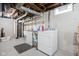 Basement laundry area with a washing machine, dryer, laundry sink, shelving, and exposed pipes at 5946 Guilford Ave, Indianapolis, IN 46220