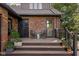 Inviting covered front porch with beautiful plants, seating, and a brick exterior at 5946 Guilford Ave, Indianapolis, IN 46220