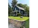 Charming home with a covered porch, manicured lawn, stone wall and lush trees at 6107 Broadway St, Indianapolis, IN 46220