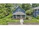 Charming blue two-story home featuring a cozy front porch with white columns and lush landscaping at 6107 Broadway St, Indianapolis, IN 46220
