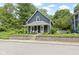 Blue two-story home showcasing a charming front porch, lush landscaping, and brick retaining wall at 6107 Broadway St, Indianapolis, IN 46220