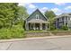 Blue two-story home showcasing a charming front porch and lush landscaping with brick retaining wall at 6107 Broadway St, Indianapolis, IN 46220