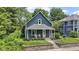Charming blue two-story home featuring a cozy front porch with chairs and manicured landscaping at 6107 Broadway St, Indianapolis, IN 46220