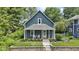 Charming blue two-story home featuring a cozy front porch with white columns and lush landscaping at 6107 Broadway St, Indianapolis, IN 46220
