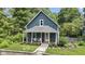 Charming blue home boasting a welcoming front porch with chairs and manicured landscaping at 6107 Broadway St, Indianapolis, IN 46220