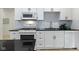 Modern kitchen with white cabinetry, stainless steel appliances, black countertop and light backsplash at 6107 Broadway St, Indianapolis, IN 46220