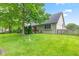 Backyard view of the house showcasing a well-manicured lawn, mature trees, and a wooden fence at 6980 White Oak Dr, Avon, IN 46123