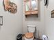 This half bath includes a toilet with wooden seat, wood cabinet, and unique owl wall art at 6980 White Oak Dr, Avon, IN 46123