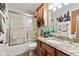 Cozy bathroom featuring a tub with shower, granite countertops, and wood cabinetry, perfect for relaxation at 6980 White Oak Dr, Avon, IN 46123