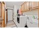 Practical laundry area with modern white machines, oak cabinets, and a utility sink for added convenience at 6980 White Oak Dr, Avon, IN 46123