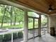 Cozy screened porch with a wood ceiling and fan, providing picturesque views of the outdoor landscaping and fire pit at 7106 Royal Oakland Dr, Indianapolis, IN 46236