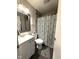 Cozy bathroom featuring gray tiled walls, patterned shower curtain and modern white vanity at 729 Maple Ln, Brownsburg, IN 46112