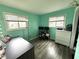 Bright bedroom featuring gray wood floors, fresh light teal paint, and two windows for natural light at 729 Maple Ln, Brownsburg, IN 46112